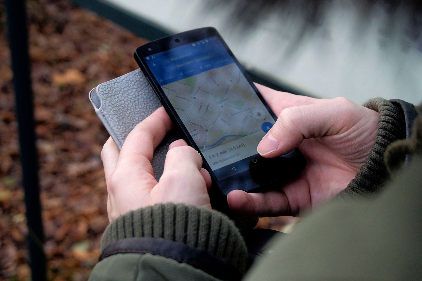 Close-up of hands using a map app on a smartphone outdoors, showcasing GPS navigation
