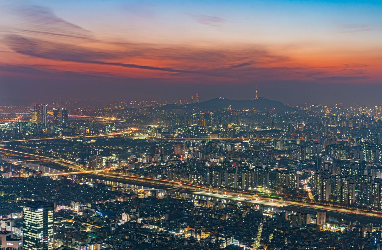 Breathtaking aerial view of illuminated Seoul cityscape at dusk with vibrant sunset sky