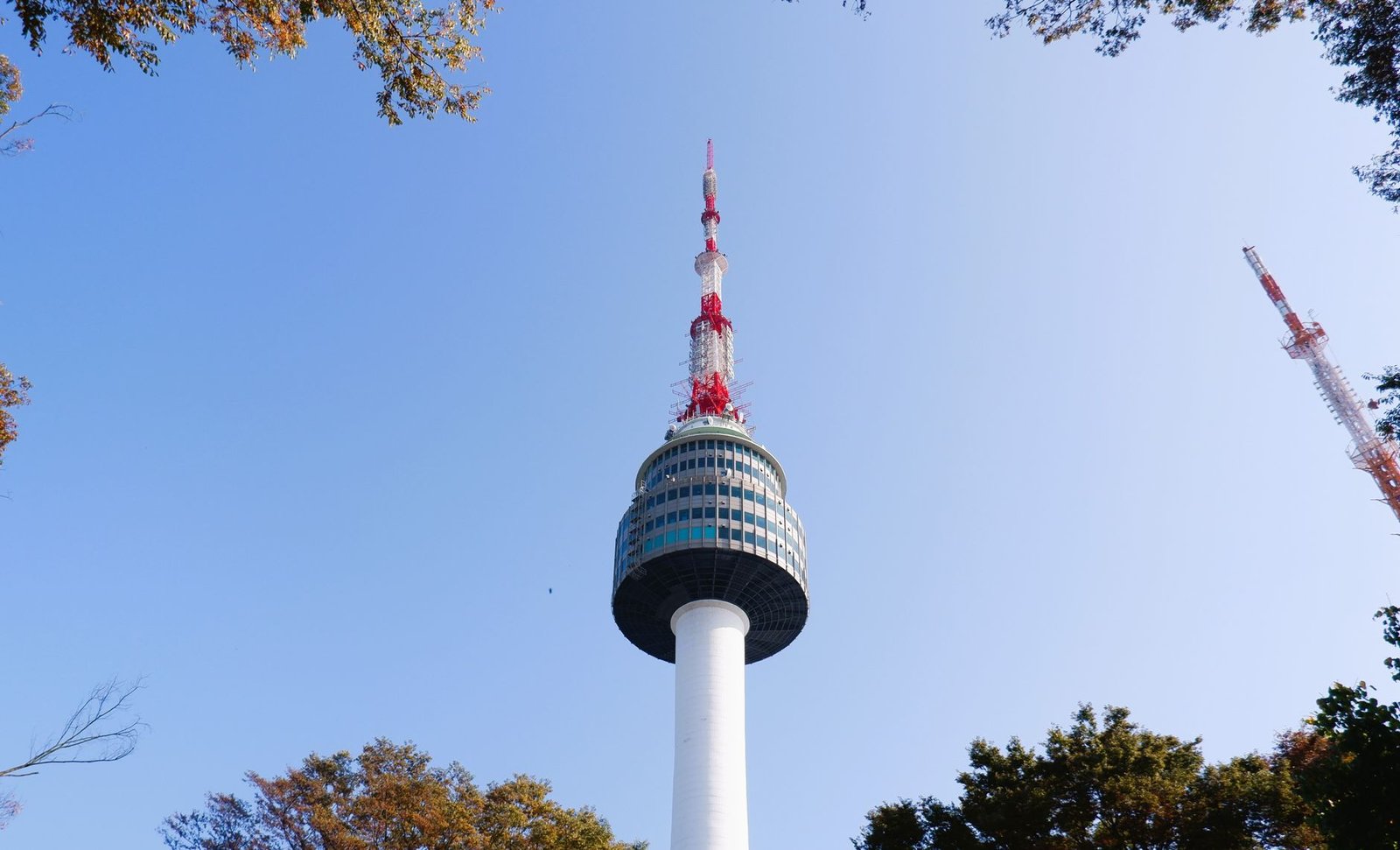 Namsan Seoul Tower rises into a clear blue sky surrounded by autumn foliage