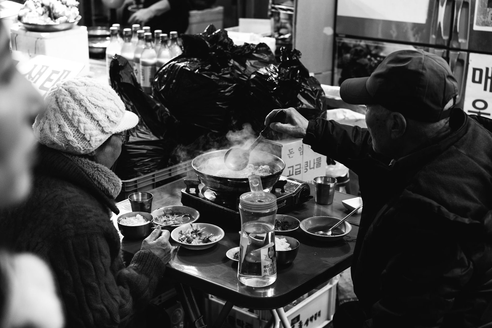 A couple enjoys steaming street food in a vibrant Seoul market