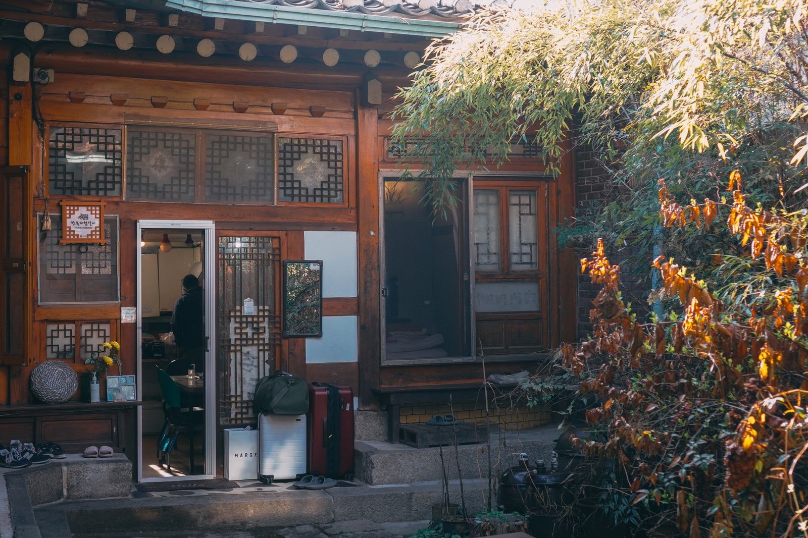 Cozy Seoul hanok featuring a traditional facade beside lush plants in a rustic setting
