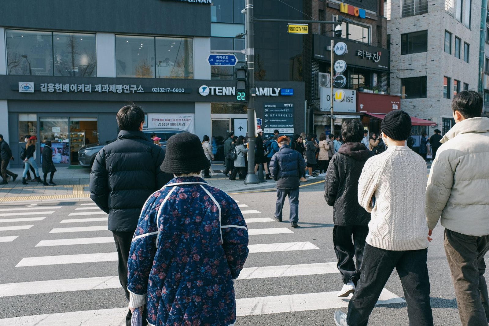 People crossing a bustling street in Seoul, South Korea, on a bright day, showcasing urban life