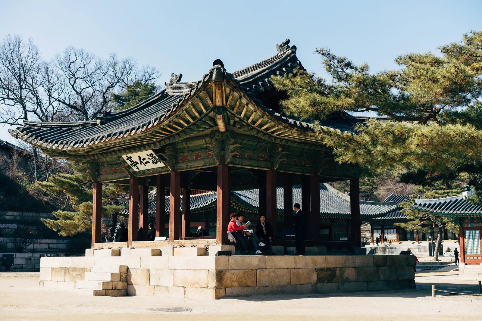 A serene view of visitors at a traditional Korean pavilion in Gyeongbokgung Palace, Seoul