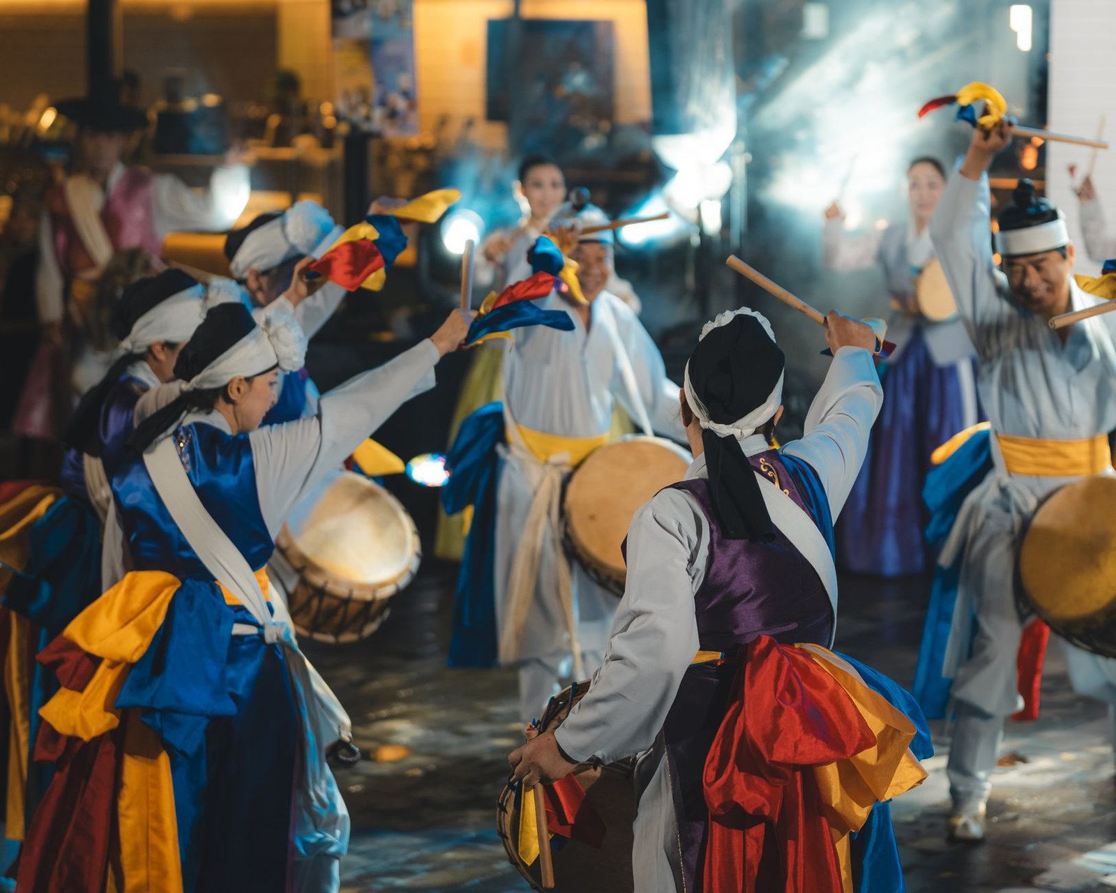 Group performing a vibrant traditional Korean dance outdoors with colorful costumes and drums