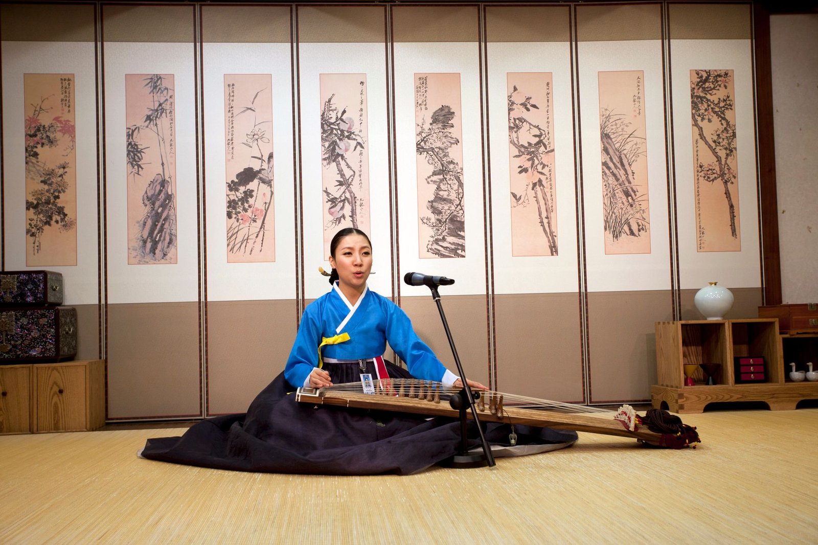 Young woman in Hanbok performing with a gayageum in a Korean traditional setting