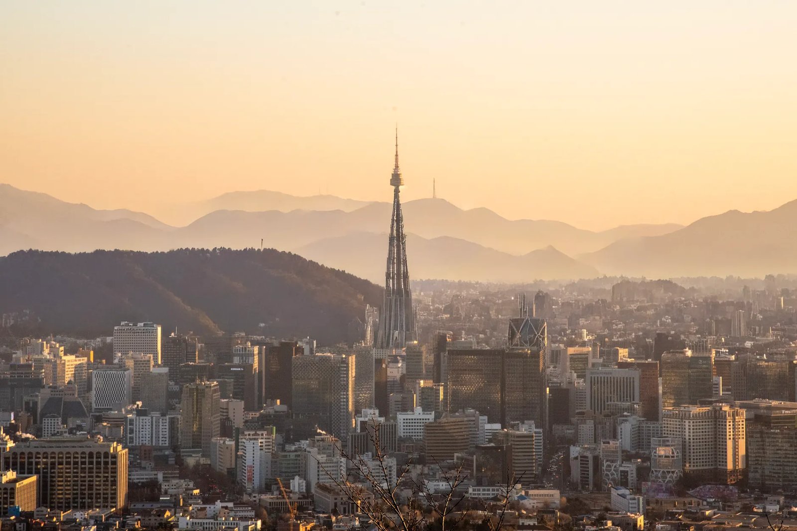 A panoramic view of Seoul's skyline during sunset, featuring Namsan Tower among skyscrapers