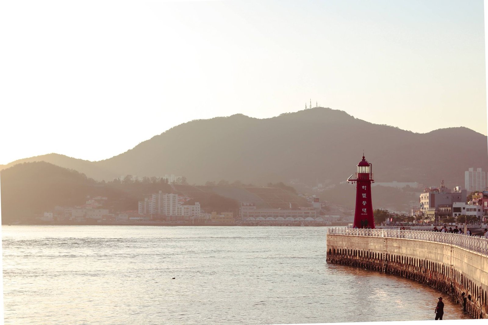 A peaceful sunset view of a lighthouse and coastal city in South Korea