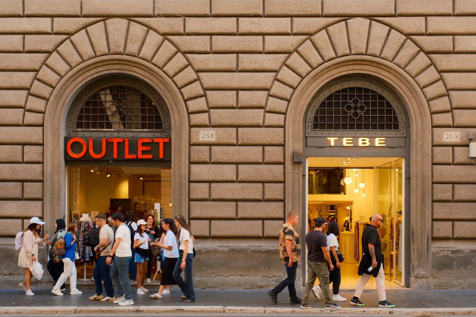People walking past outlet stores in Florence, Italy under classic architecture